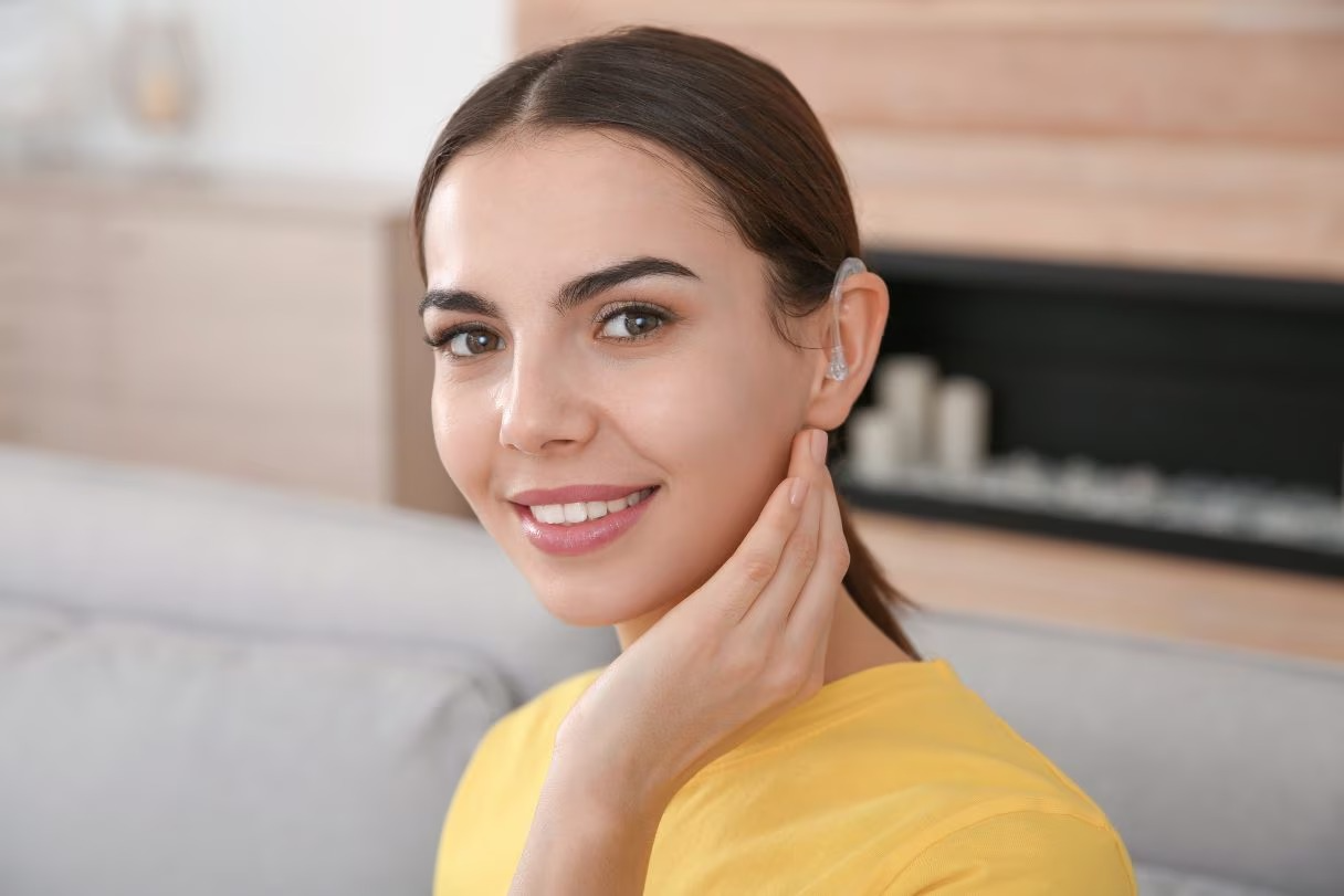 Woman wearing a behind-the-ear hearing aid at home
