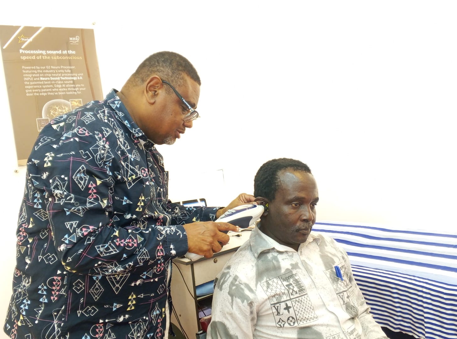 Lead audiologist performing tympanometry on a patient's left ear with a handheld probe